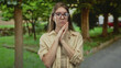 © Krakenimages.com - Young blonde woman wearing glasses and a beige shirt clasping hands near chin among tree trunks in forest; introspection reflection thought doubt.