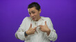© Krakenimages.com - Young hispanic man gesturing confidently against isolated purple background wearing white shirt and earrings in studio setting