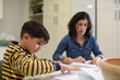 © Antonio Recena - Mother and son making paper airplanes and crafts together in the kitchen at home