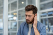 © Liubomir - Man holding hand to his ear, experiencing discomfort and pain from an earache, tinnitus, or hearing problem, indicating a health issue requiring treatment