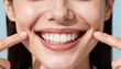 © igor.nazlo - Professional close-up of smiling woman’s mouth showing perfect teeth, index fingers pointing at cheeks, clean pale blue-grey background, banner format
