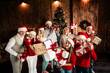 © deagreez - Happy family celebration indoors with Christmas gifts around a decorated tree in a warm cozy living room