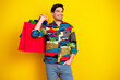 © deagreez - Young man with a colorful shirt carries shopping bags against a bright yellow background for summer fashion advertising and shopping promotion