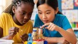 © True Stock - Robotics STEM Project: Two young girls of different ethnicities work intently on a homemade robot, focused on sparking a circuit in their science class.