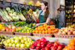 © JackF - Friendly woman seller laying out ripe bell peppers on a showcase in a supermarket