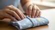 © Octopus16 - Person Folding Light Blue Baby Clothes with Cloud and Sun Pattern on Wooden Table