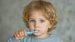 © Oulaphone - A young child with curly hair brushes their teeth, showcasing a moment of daily hygiene in a softly lit environment.