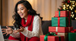 © AucArtStudio - Young woman in cozy sweater and red scarf smiling during virtual holiday call celebrating christmas and new year with gifts and warm end of year cheer