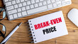 © Iryna - BREAK-EVEN PRICE text on spiral notepad with keyboard, mouse, glasses and pen on wooden desk
