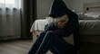 © Cliff - Upset young woman with face hidden by hoodie in bedroom holding pillow