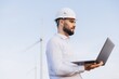 © anatoliycherkas - Engineer working with laptop analyzing wind turbine data for sustainable energy production