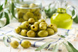© Igor Dudchak - marinated pitted green olives and olive oil on a white kitchen table, selective focus.