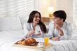 © New Africa - Happy couple enjoying delicious breakfast in bed. Hotel room service