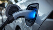 © Dragonboyr - Electric car charging port glowing blue with power cable connected, a symbol of modern sustainable transportation and clean energy.