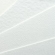 © elenavolf - Close-up of textured white paper with subtle patterns.