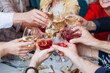 © tsuguliev - Group of guests celebrate and raise glasses, toasting and cheering with alcohol glasses with wine and champagne in the restaurant on corporate christmas birthday party event or wedding celebration