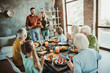 © deagreez - Funny creative family thanksgiving gathering scene with loved ones sharing dinner around long table with turkey candles and joyful conversation