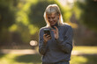© Zoran Jesic - Young woman smiling using smartphone in park