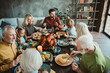 © deagreez - Happy family Thanksgiving dinner with multiple generations sharing a big turkey meal smiling and enjoying a festive autumn table filled with food friends and laughter
