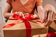 © Lux Images - Close-up of hands wrapping Christmas gift with red ribbon