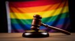 © Space Priest - Wooden gavel on desk against rainbow flag symbolizing lgbtq justice and equality