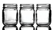 © irawan - Three empty glass preserving jars stand aligned on a reflective surface against a bright background