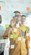 © volha_r - Business people team brainstorming, sharing strategy on glass whiteboard with colorful sticky notes, working collaboratively in bright office