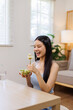 © David - Happy multiracial asian woman eating healthy salad for lunch at home office.Break from work. Copy space. Healthy lifestyle concept.