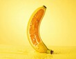 © Ingrid - A single banana, cut in half lengthwise, stands upright against a bright yellow background. The exposed interior reveals orange flesh with small seeds. Water droplets cover the surface.