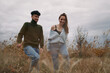 © SHOTPRIME STUDIO - A candid outdoor image of a young couple walking through tall grass on an overcast day, capturing authentic connection and credible natural emotions in a casual lifestyle moment.