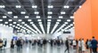 © Norah Allen - Blurred business people walking in modern exhibition hall with bright ceiling lights, abstract event background, corporate expo or conference interior, large indoor trade show crowd atmosphere