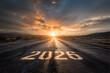 © Trendy Graphics - The new year 2026 is painted on a wet asphalt road leading towards a dramatic sunset with a bright sunburst