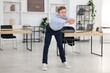© New Africa - Young businessman doing stretching exercise in office