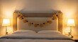 © Kerkez2 - Warmly lit bedroom with garland adorning headboard featuring white bedding and two lamps