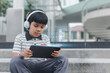 © eakgrungenerd - Smart child using tablet with AI assistant hologram, wearing headphones, representing artificial intelligence, digital learning, and futuristic virtual education in modern technology era.