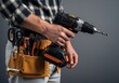 © PutriAlifiyah - Carpenter holding cordless drill with tool belt in workshop