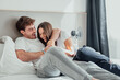 © Daniel - A young couple lies in bed, laughing and playfully teasing each other. Their smiles and playful touches show joy, closeness, and love, sharing a fun, relaxed moment at home.
