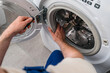 © brizmaker - Home repair service fixing a washing machine in a modern laundry room