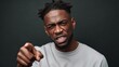 © Nataliia_Trushchenko - African American man with short dreadlocks, expressing strong emotions while pointing aggressively, showcasing intensity and passion in a dramatic portrait against a dark background