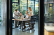 © ty - A modern office interior, featuring a blurred view of workers at desks, through a glass partition.