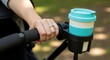 © photoplotnikov - Female hand with reusable cup on stroller in park setting