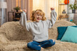 © Andrii Iemelianenko - Happy young teenager girl celebrating victory with cheerful and excited smile at home. Caucasian child kid sitting on a sofa, expressing happiness and joy after receiving good news or winning a game