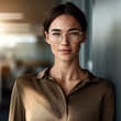 © visoot - Confident woman wearing glasses and brown blouse standing indoors, natural light, professional atmosphere, modern office background
