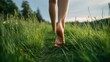 © mila103 - Bare feet explore soft grass in a tranquil field under a serene sky evoking a sense of calm.