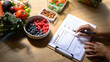 © Prathankarnpap - Nutritionist writing a healthy meal plan with fresh fruits, vegetables, and nuts on the table