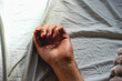 © ada35 - Close-up of a human hand resting gently on a bed sheet under natural morning light. The minimalist scene evokes calmness, comfort, relaxation, and peaceful domestic moments.