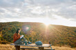 © we.bond.creations - Young woman journaling on a picnic table amidst autumn foliage during golden hour, finding inspiration in nature