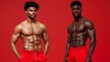 © Raul - Two muscular men stand shirtless against a vivid red backdrop, showcasing their physiques and toned abs.