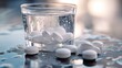 © Volodymur - Clear glass of water with white medication pills dissolving inside. More white tablets are scattered on a wet reflective surface with drops.