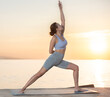 © JackF - Active experienced woman fitness club teacher performs yoga asana on mat on seashore at sunset outdoors. Concept of healthy lifestyle